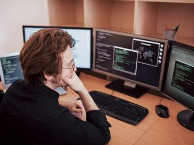 male-programmer-working-on-desktop-computer-with-many-monitors-at-office-in-software-develop-company.jpg